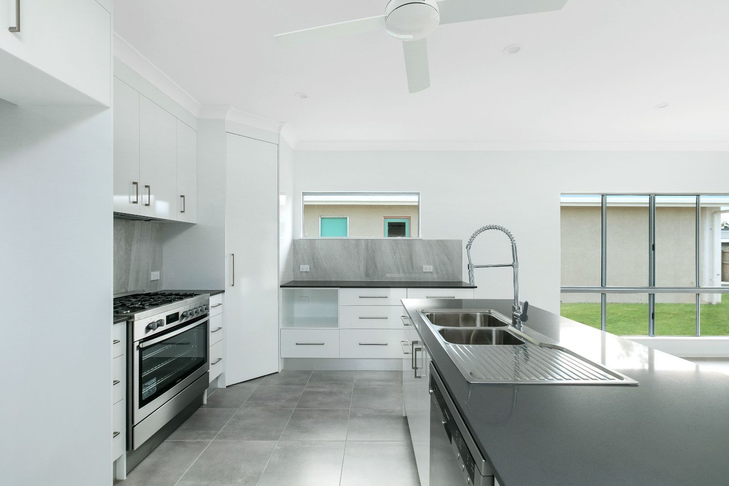 A Kitchen With Two Sinks and a Ceiling Fan — Ashlee Jones Homes in Gordonvale, QLD