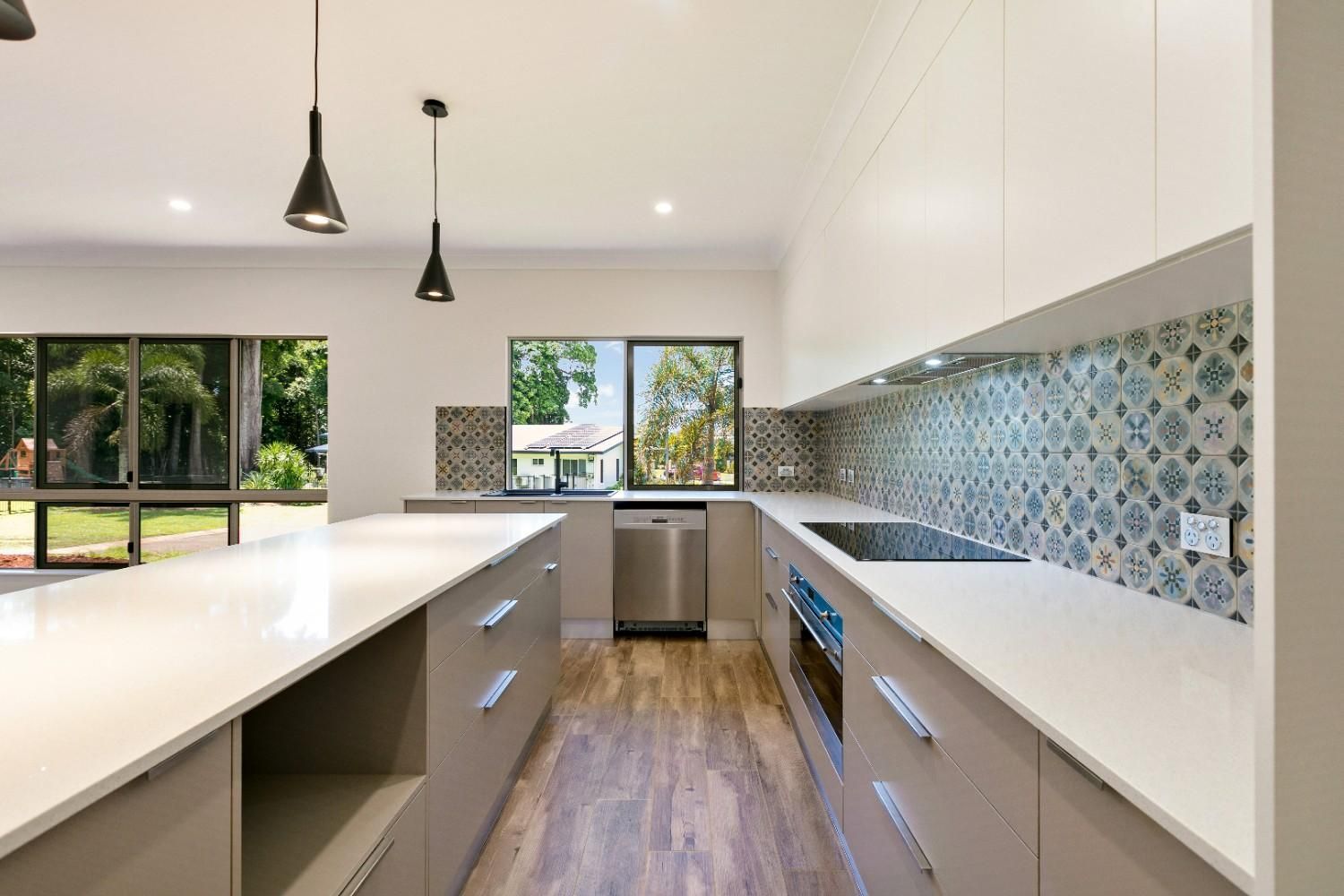 A Kitchen With White Cabinets, a Stove, a Dishwasher, and a Large Island — Ashlee Jones Homes in Gordonvale, QLD