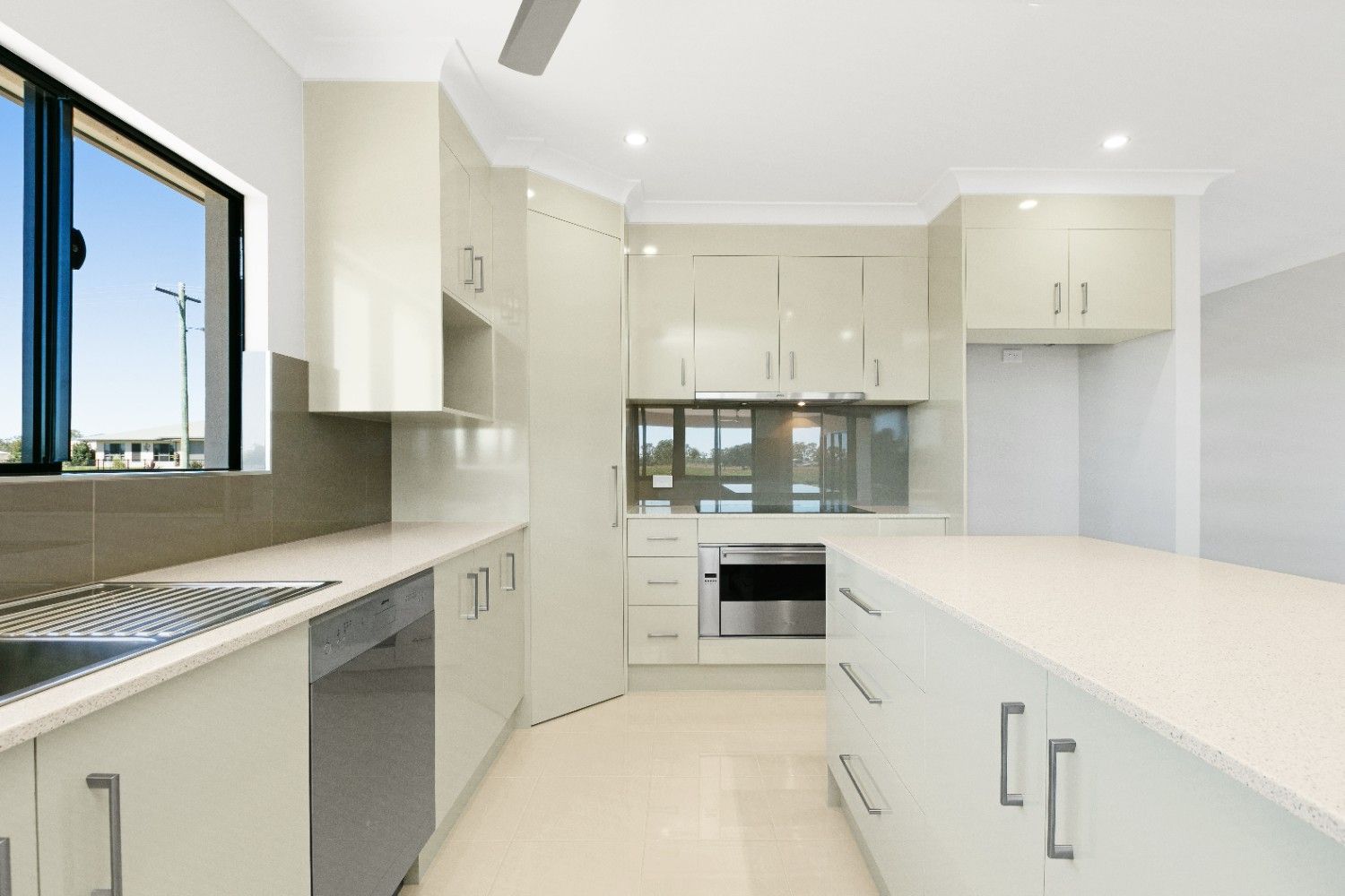 A Kitchen With White Cabinets, Stainless Steel Appliances and a Ceiling Fan — Ashlee Jones Homes in Gordonvale, QLD