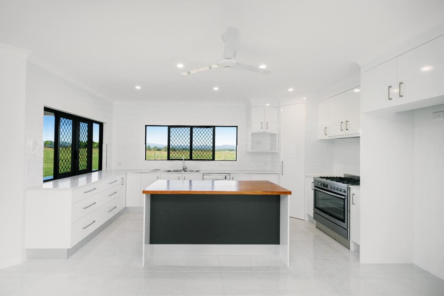 A Kitchen With White Cabinets and a Black Island in the Middle — Ashlee Jones Homes in Gordonvale, QLD