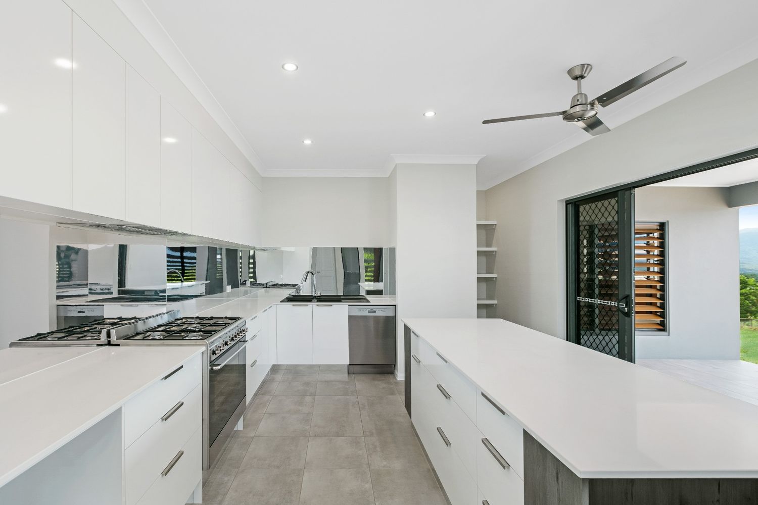 A Kitchen With White Cabinets and a Ceiling Fan — Ashlee Jones Homes in Gordonvale, QLD