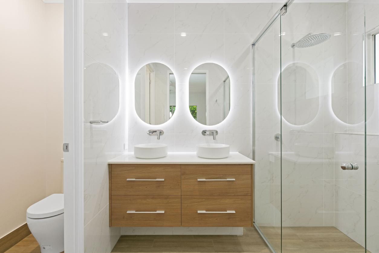 A Bathroom With Two Sinks, a Toilet, and a Walk in Shower — Ashlee Jones Homes in Gordonvale, QLD
