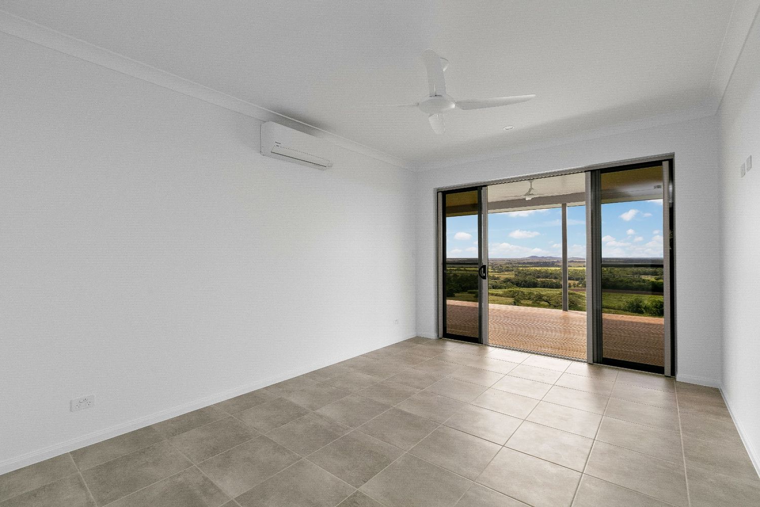 An Empty Living Room With Sliding Glass Doors and a Ceiling Fan — Ashlee Jones Homes in Gordonvale, QLD