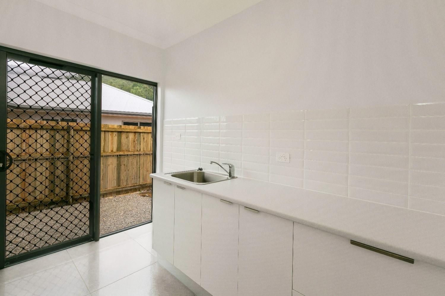 An Empty Kitchen With a Sink and a Sliding Glass Door — Ashlee Jones Homes in Gordonvale, QLD