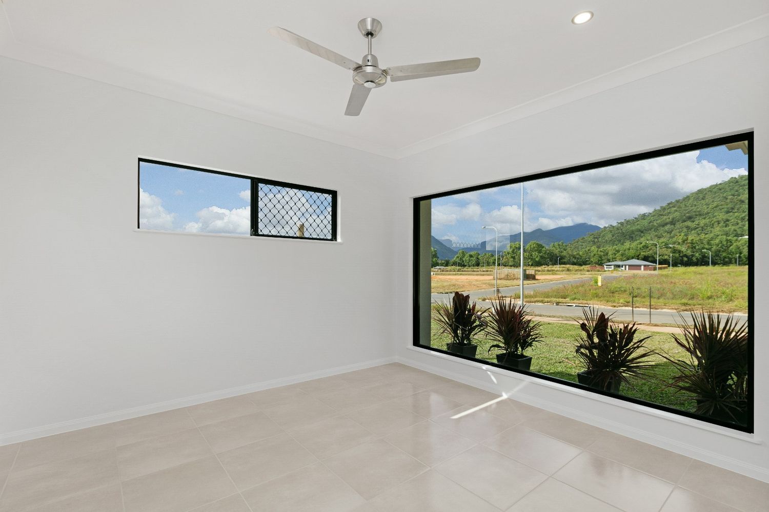 An Empty Room With a Large Window and a Ceiling Fan — Ashlee Jones Homes in Gordonvale, QLD