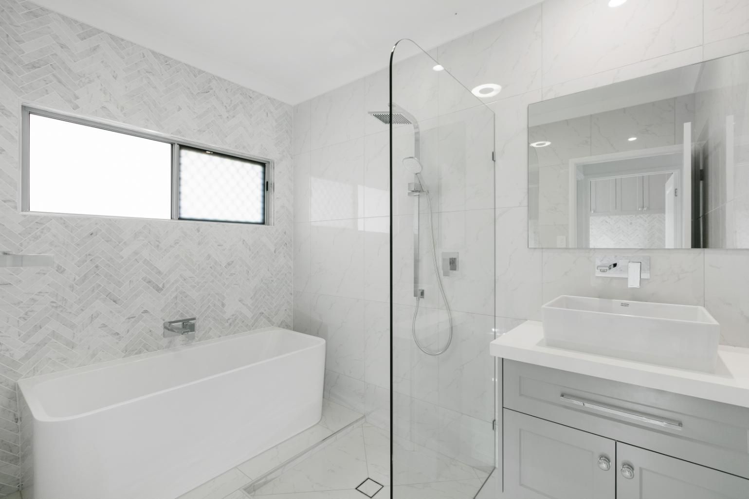 A Bathroom With a Bathtub, Sink, Shower and Mirror — Ashlee Jones Homes in Gordonvale, QLD