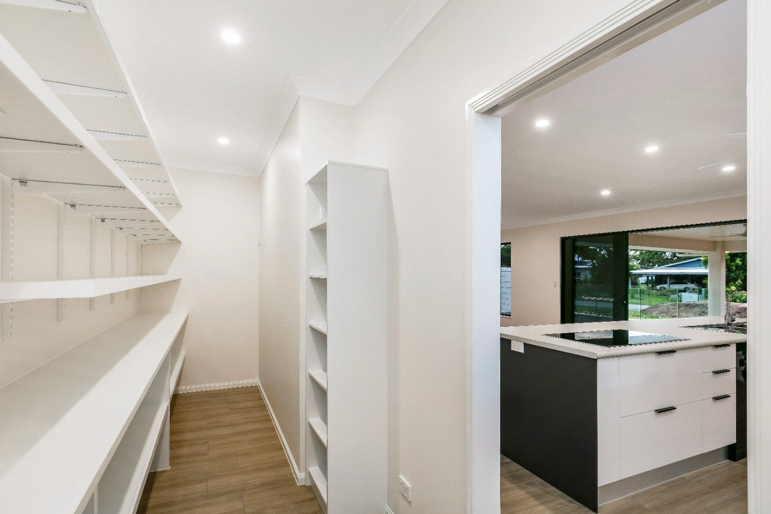 A Hallway Leading to a Kitchen With Shelves and a Sink — Ashlee Jones Homes in Gordonvale, QLD