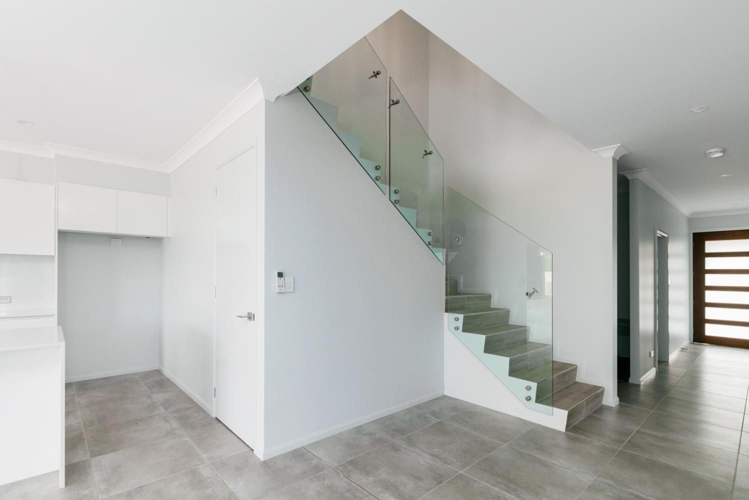 An Empty Room With a Staircase and a Glass Railing — Ashlee Jones Homes in Gordonvale, QLD