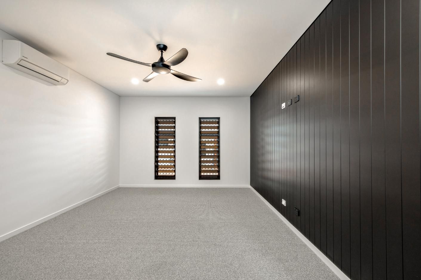 An Empty Room with A Ceiling Fan and Two Windows — Ashlee Jones Homes in Gordonvale, QLD