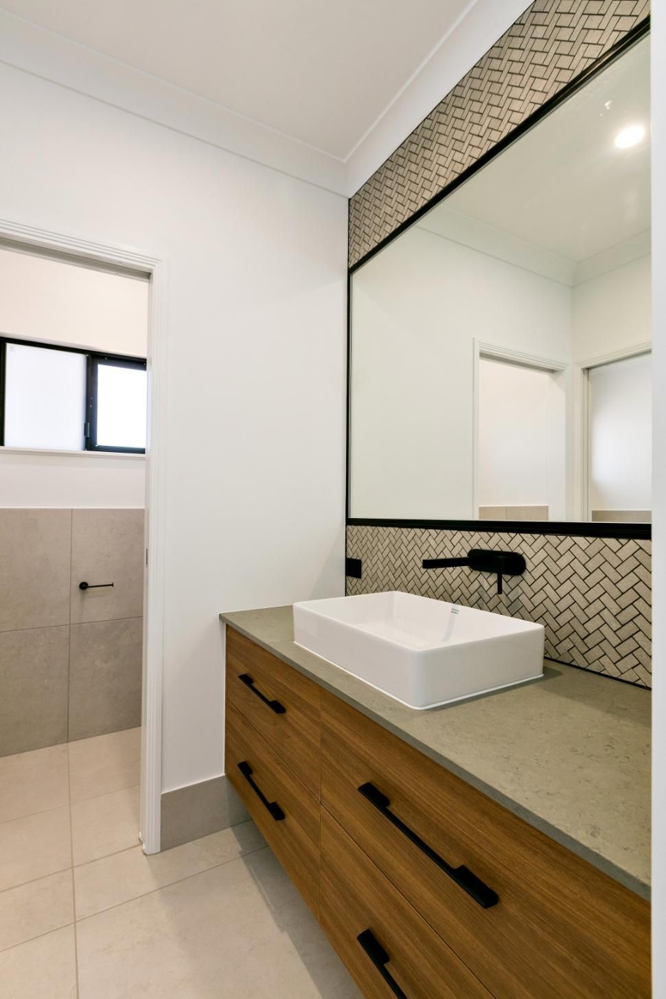 A Bathroom With a Sink, Mirror and Drawers — Ashlee Jones Homes in Gordonvale, QLD