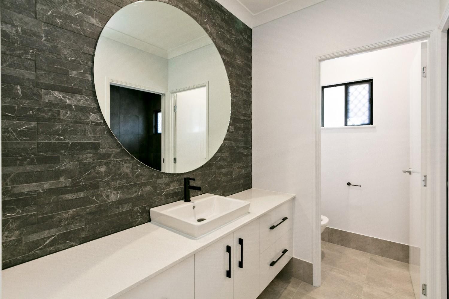 A Bathroom With a Sink and a Round Mirror  — Ashlee Jones Homes in Gordonvale, QLD