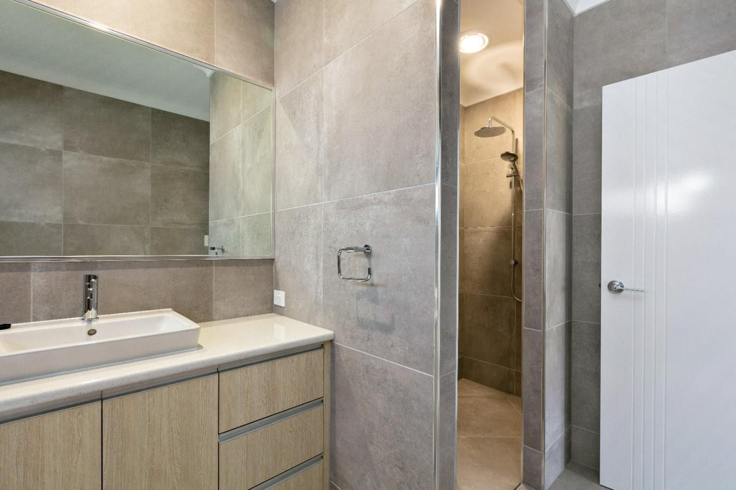 A Bathroom With a Sink, Mirror and Walk in Shower — Ashlee Jones Homes in Gordonvale, QLD