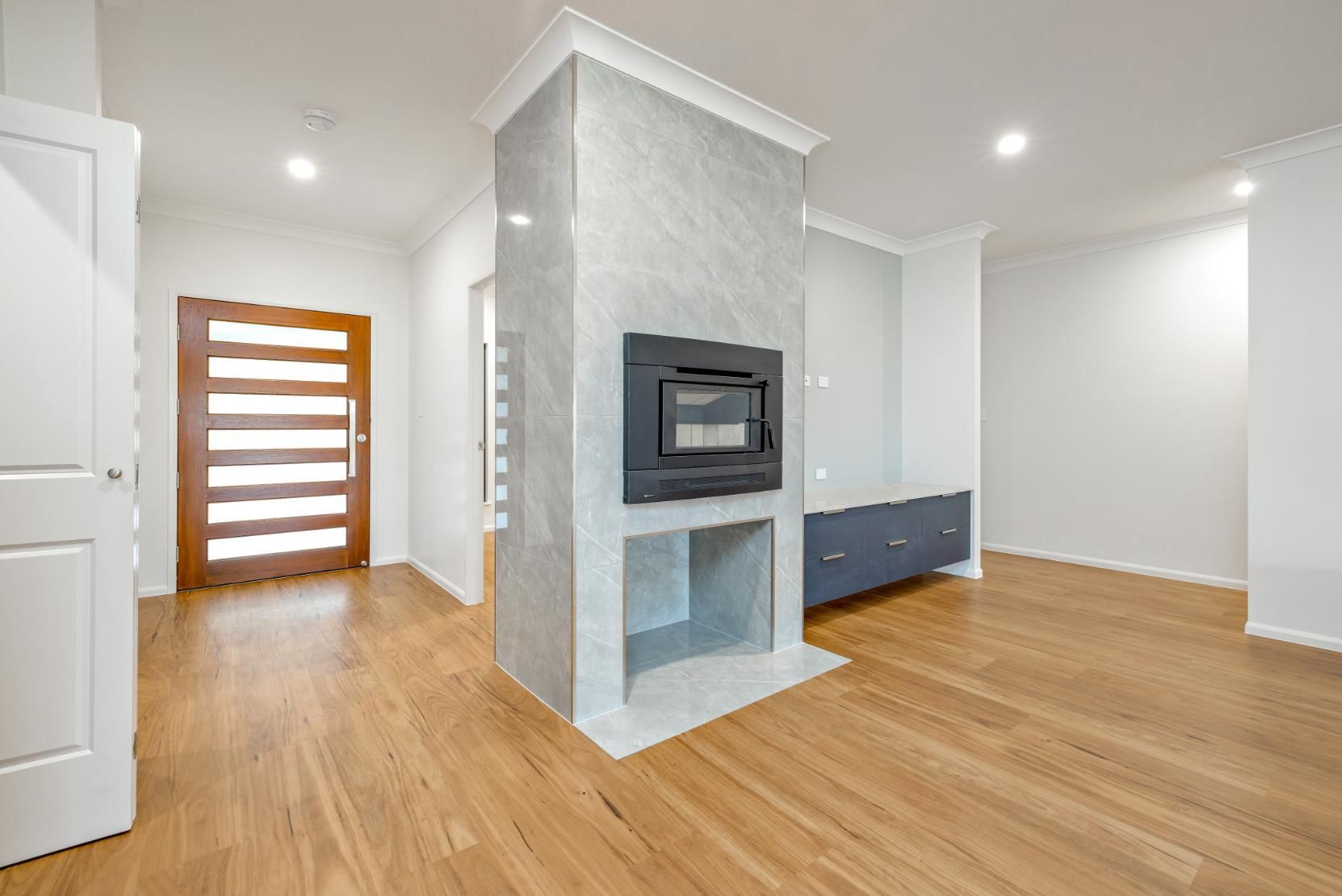 An Empty Living Room With Hardwood Floors and a Fireplace — Ashlee Jones Homes in Gordonvale, QLD