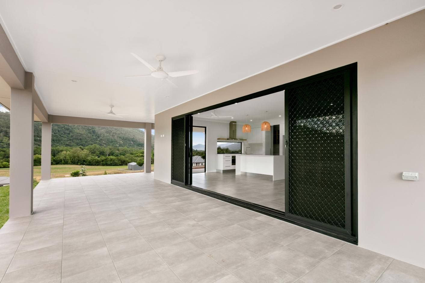 A Large Patio With Sliding Glass Doors Leading to a Kitchen — Ashlee Jones Homes in Gordonvale, QLD