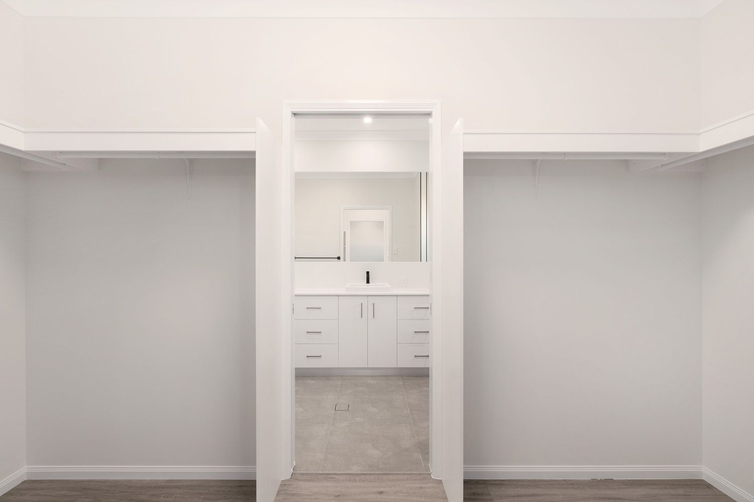 An Empty Walk in Closet With a Bathroom in the Background — Ashlee Jones Homes in Gordonvale, QLD
