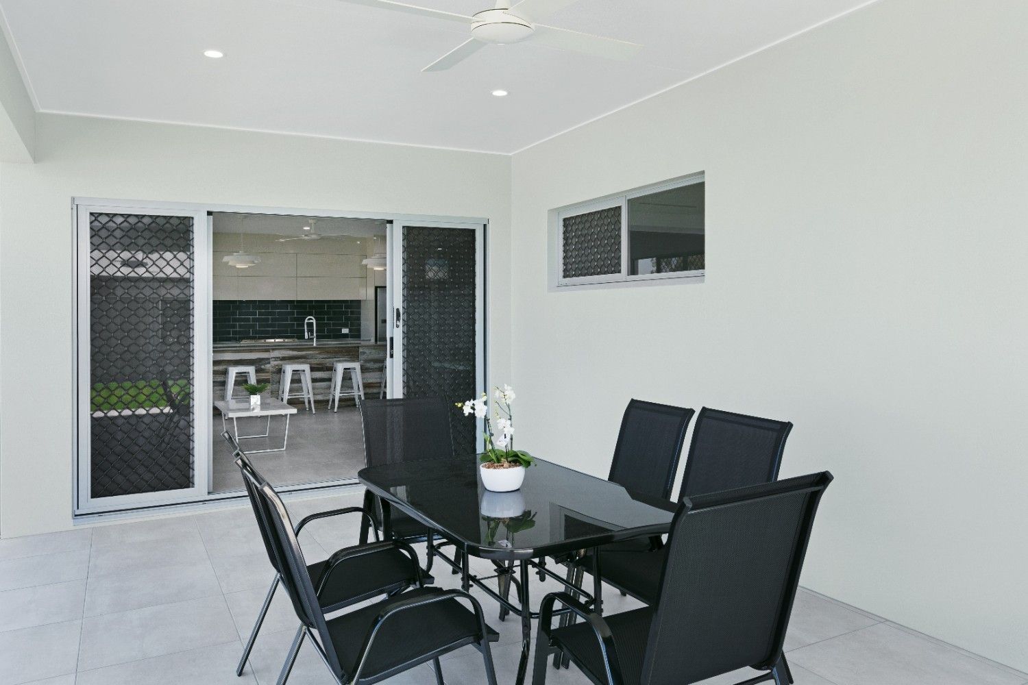 A Patio With a Table and Chairs and a Ceiling Fan — Ashlee Jones Homes in Gordonvale, QLD