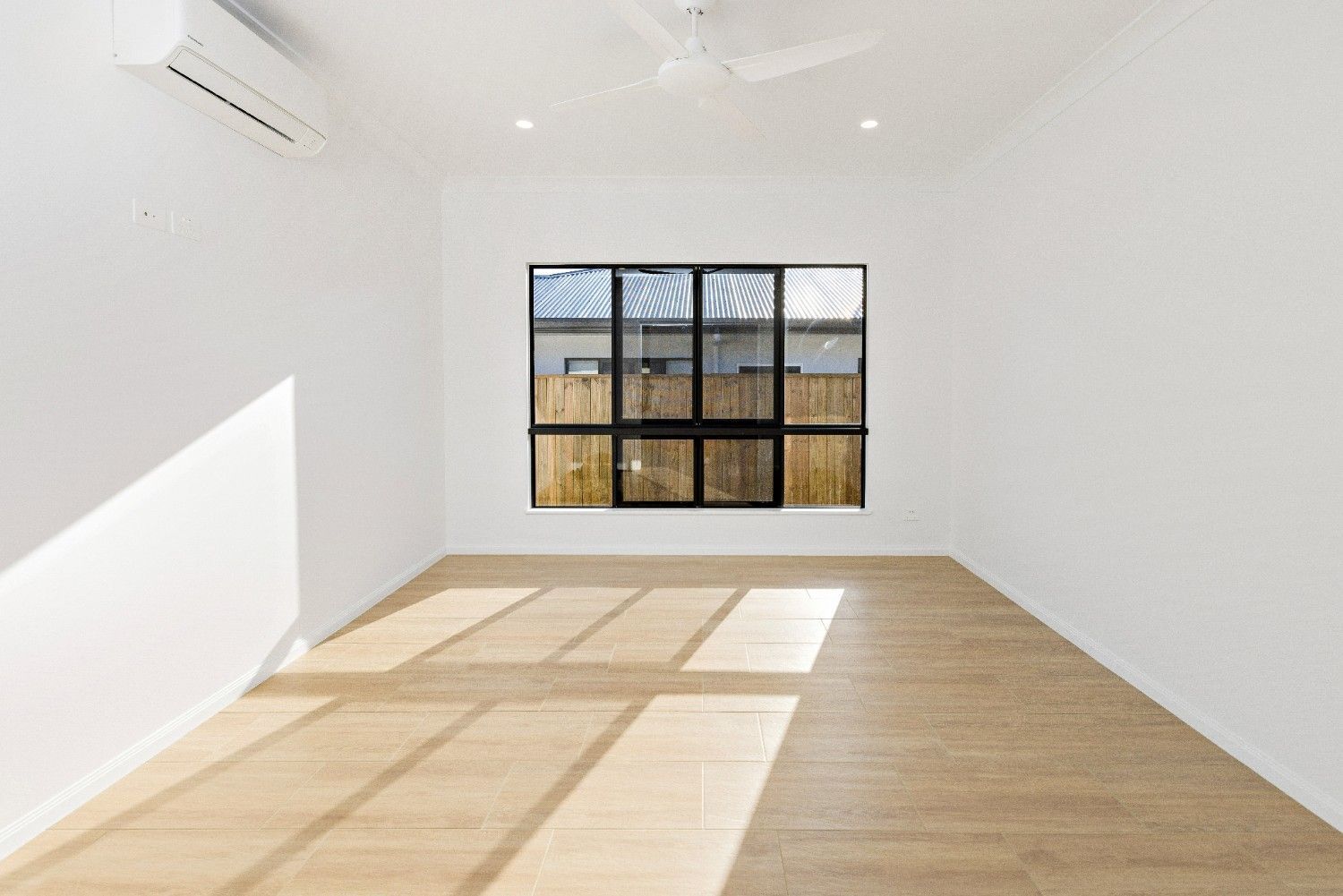 An Empty Room With a Window and a Ceiling Fan — Ashlee Jones Homes in Gordonvale, QLD