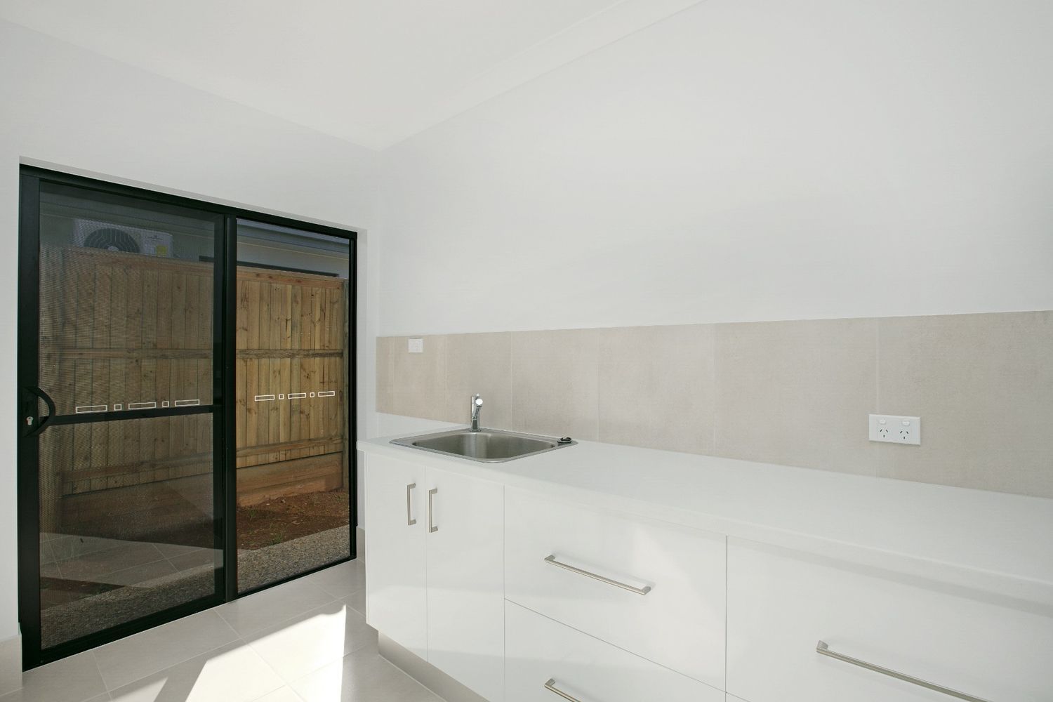 An Empty Kitchen With White Cabinets and a Sink — Ashlee Jones Homes in Gordonvale, QLD