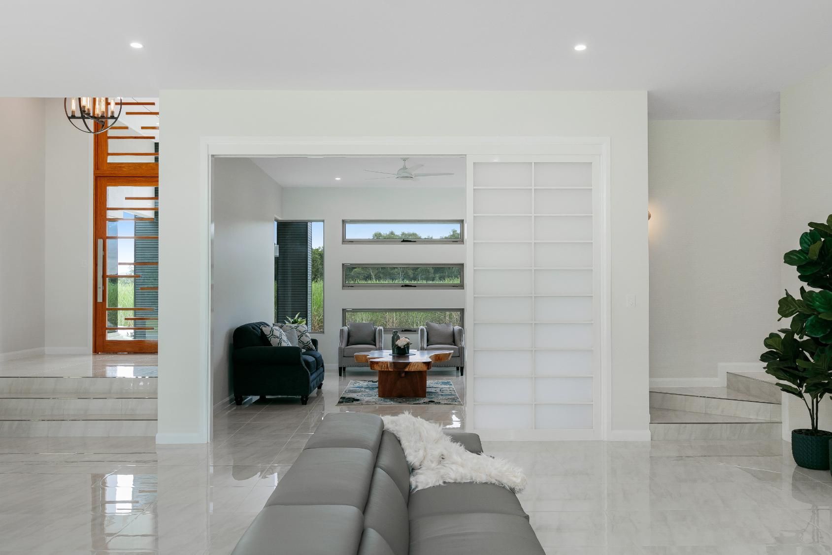 A Living Room With a Couch, Coffee Table, and Sliding Glass Doors — Ashlee Jones Homes in Gordonvale, QLD