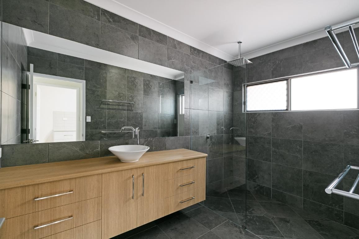 A Bathroom With a Sink, Mirror, and Walk in Shower — Ashlee Jones Homes in Gordonvale, QLD