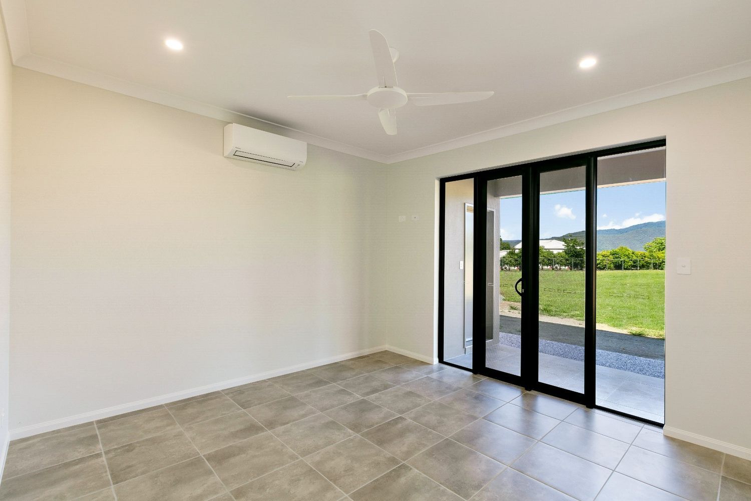 An Empty Room With Sliding Glass Doors and a Ceiling Fan — Ashlee Jones Homes in Gordonvale, QLD