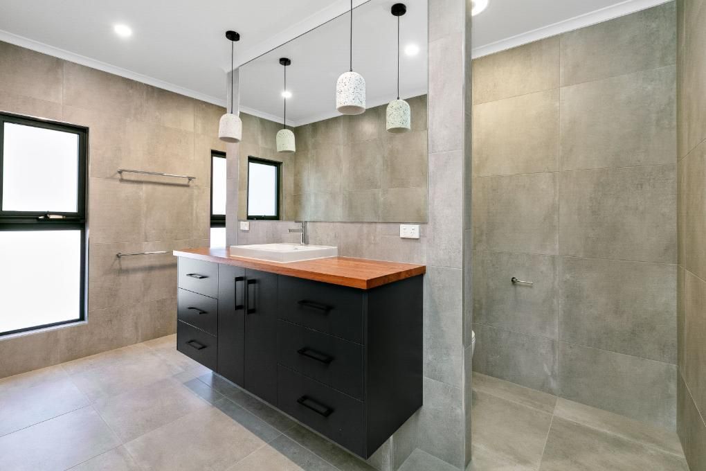 A Bathroom With a Sink, Mirror and Walk in Shower — Ashlee Jones Homes in Gordonvale, QLD
