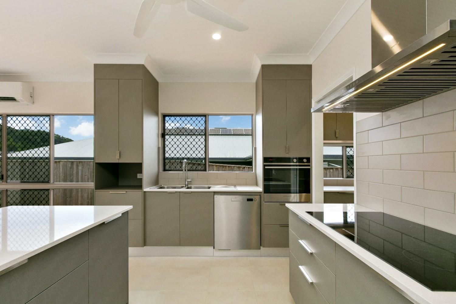 A Kitchen With Gray Cabinets and White Counter Tops — Ashlee Jones Homes in Gordonvale, QLD