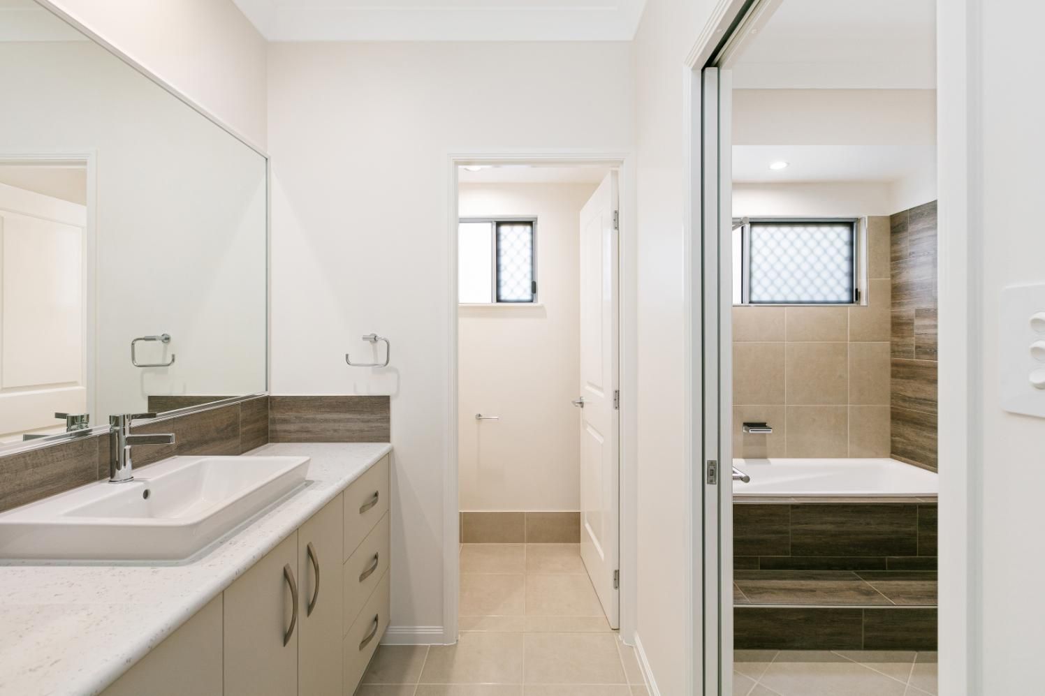 A Bathroom With a Sink, Mirror and Bathtub — Ashlee Jones Homes in Gordonvale, QLD