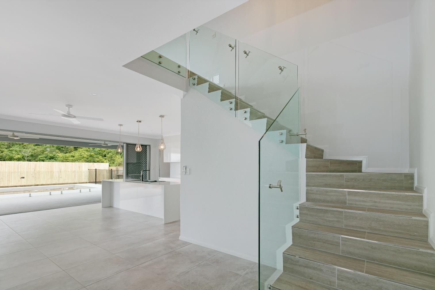 A Staircase With a Glass Railing Leading Up to the Second Floor of a House — Ashlee Jones Homes in Gordonvale, QLD