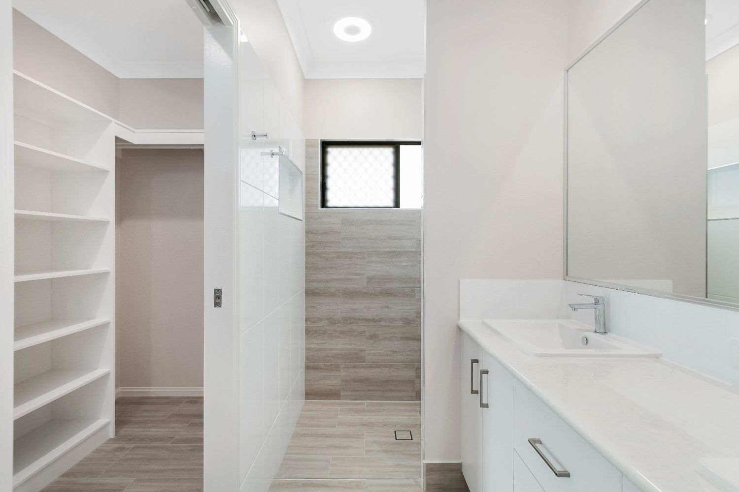 A Bathroom With a Sink, Mirror and Walk in Closet — Ashlee Jones Homes in Gordonvale, QLD