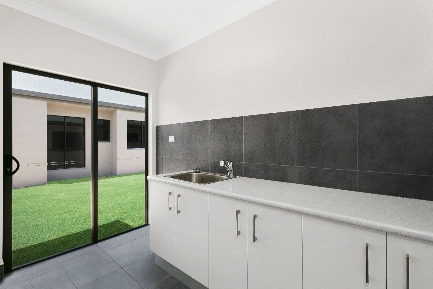 A Kitchen With White Cabinets, a Sink, and a Sliding Glass Door — Ashlee Jones Homes in Gordonvale, QLD