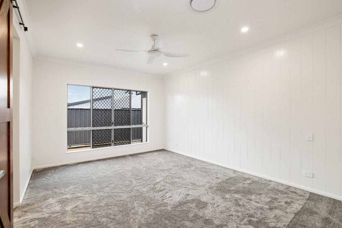 An Empty Bedroom With a Ceiling Fan and a Window — Ashlee Jones Homes in Gordonvale, QLD
