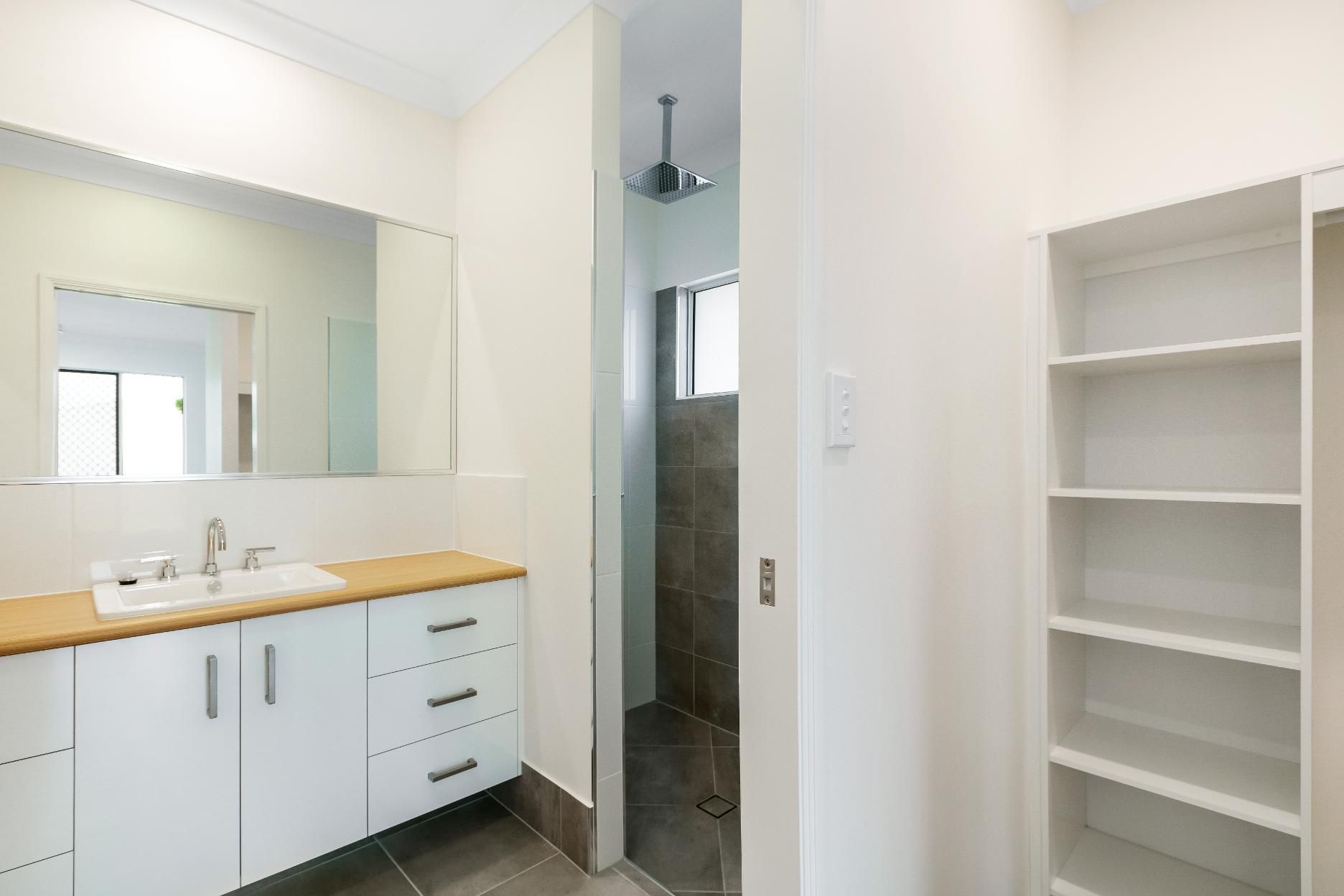 A Bathroom With a Sink, Mirror, Shelves and a Walk in Shower — Ashlee Jones Homes in Gordonvale, QLD