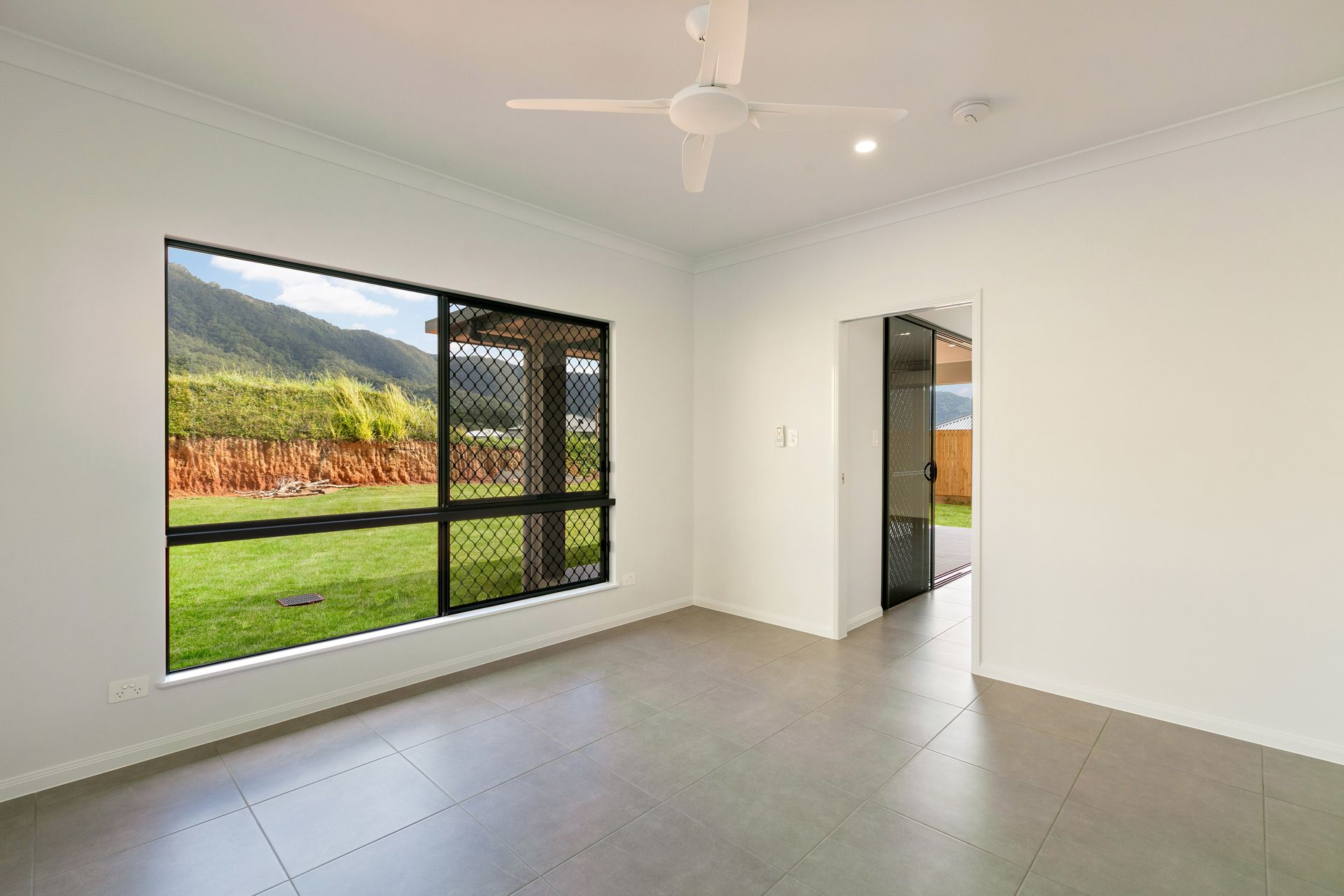 Empty Modern Room With White Walls, Tile Flooring, a Ceiling Fan — Ashlee Jones Homes in Gordonvale, QLD