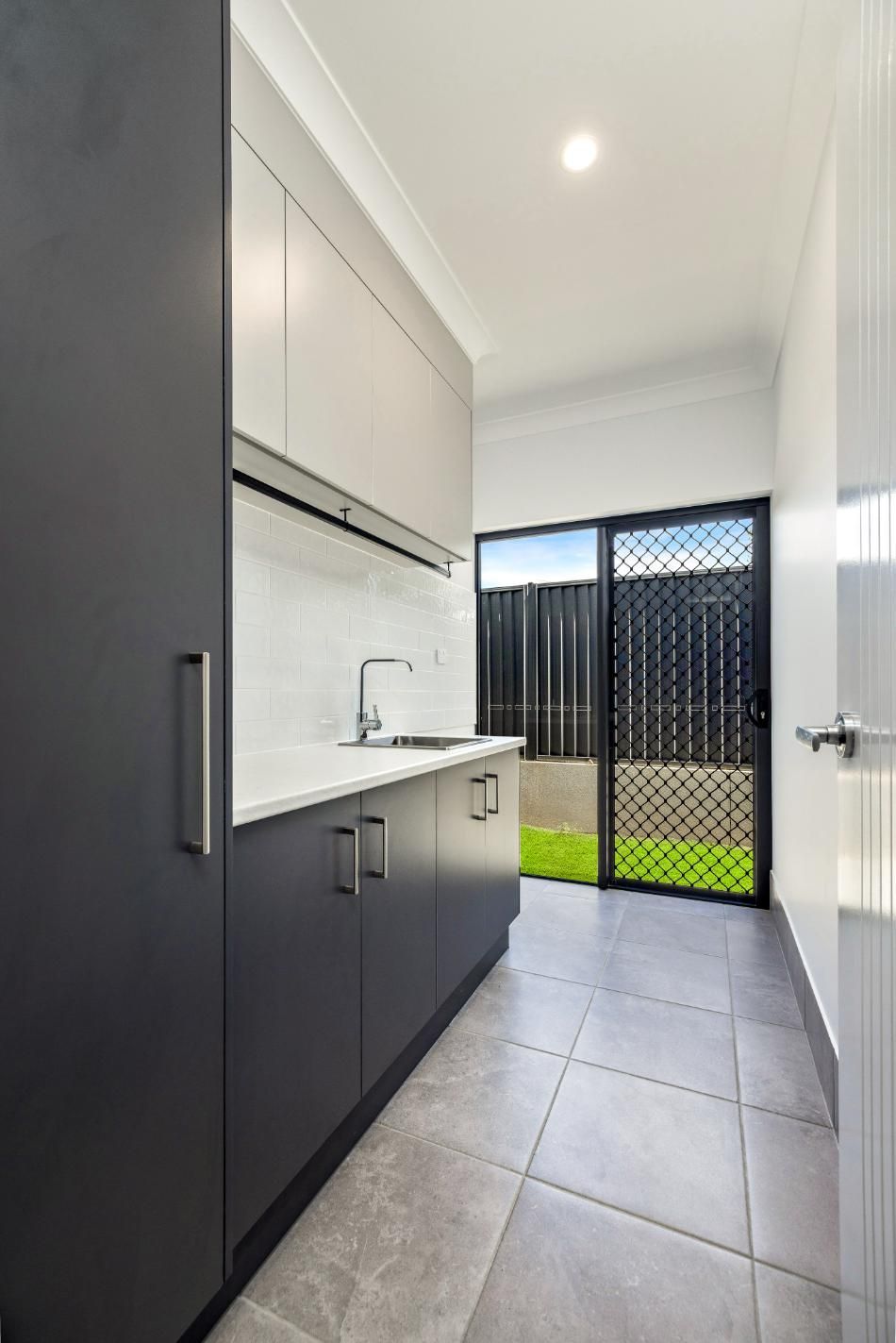 A Kitchen With Black Cabinets, a Sink, and a Sliding Glass Door — Ashlee Jones Homes in Gordonvale, QLD