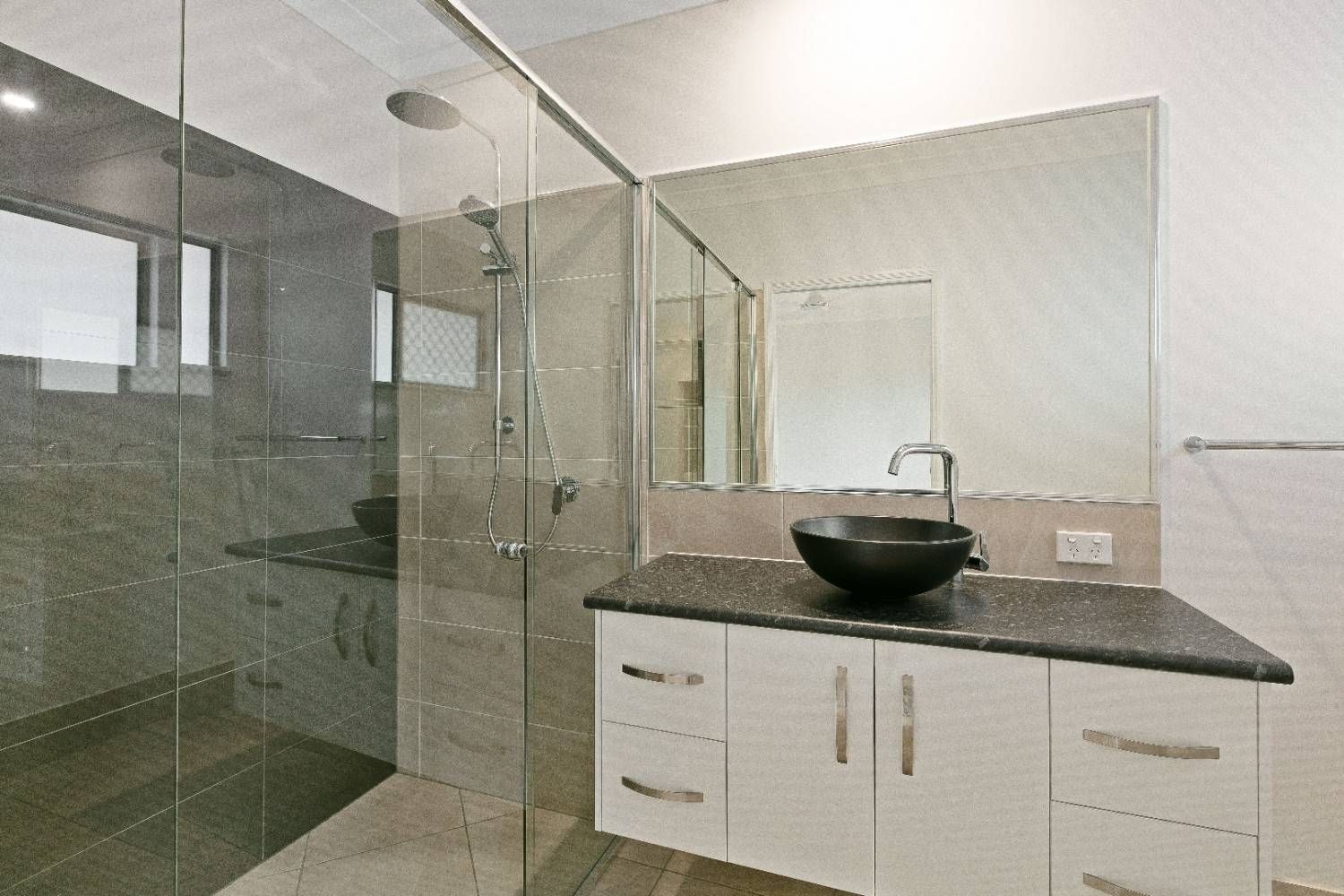 A Bathroom With a Sink, Mirror and Walk in Shower — Ashlee Jones Homes in Gordonvale, QLD