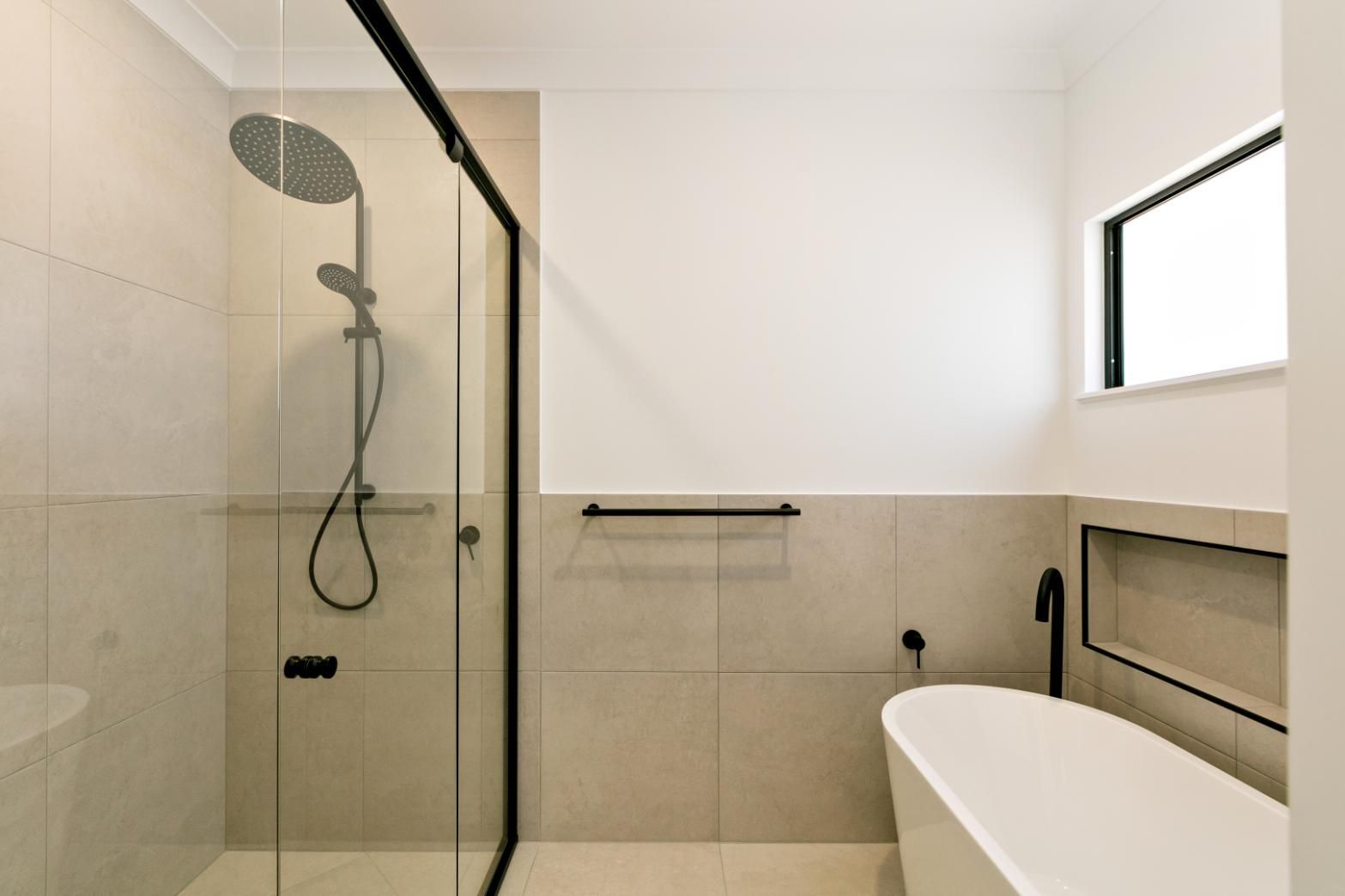 A Bathroom With a Bathtub, Shower, and Window — Ashlee Jones Homes in Gordonvale, QLD