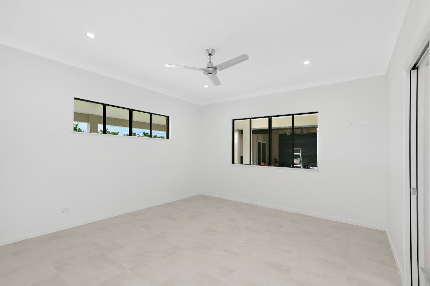 An Empty Room With a Ceiling Fan and Two Windows — Ashlee Jones Homes in Gordonvale, QLD