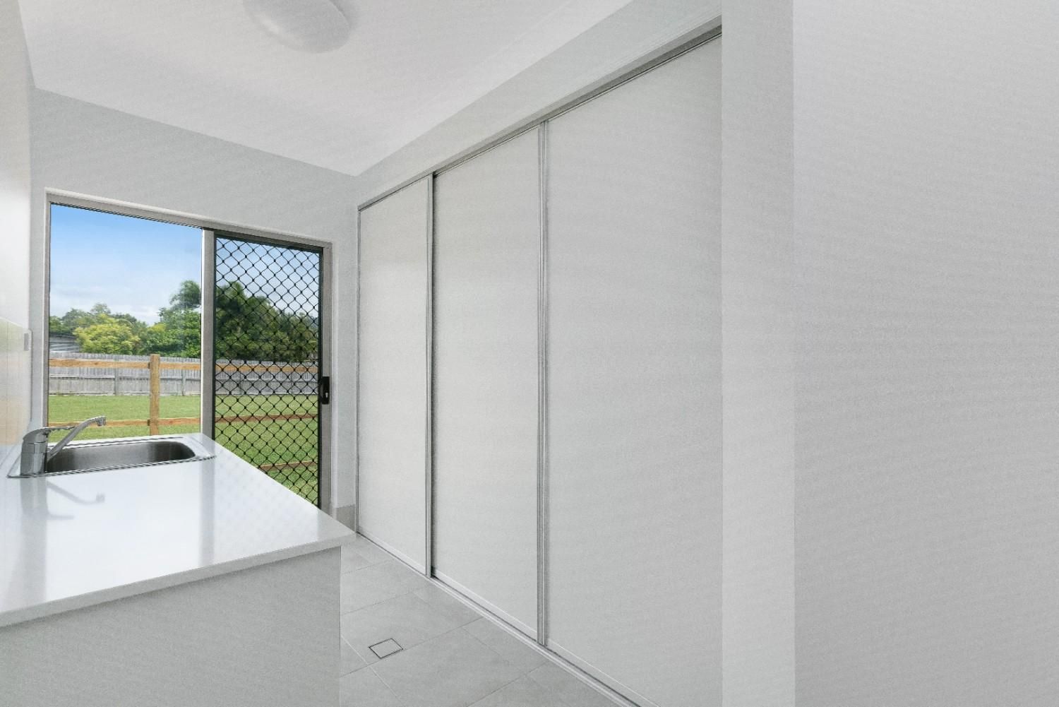 A Laundry Room With Sliding Glass Doors and a Sink — Ashlee Jones Homes in Gordonvale, QLD