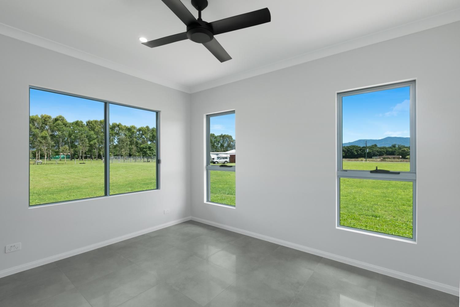 An Empty Room With Three Windows and a Ceiling Fan — Ashlee Jones Homes in Gordonvale, QLD