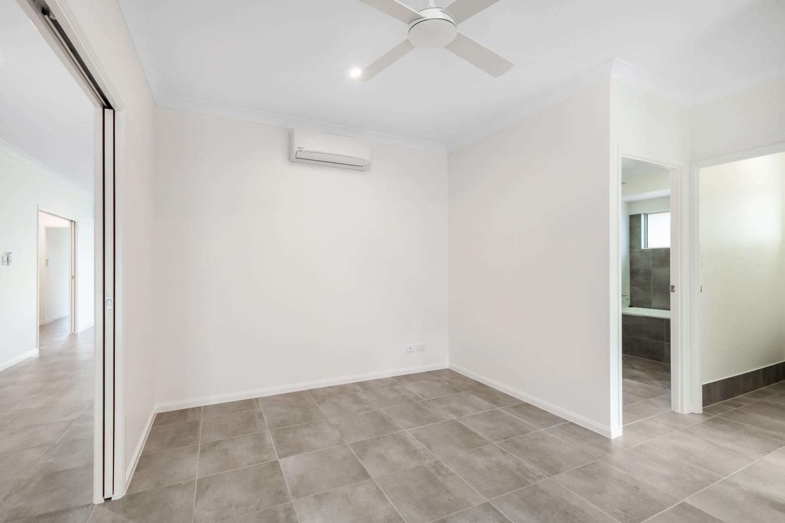 An Empty Bedroom With a Ceiling Fan and a Sliding Glass Door — Ashlee Jones Homes in Gordonvale, QLD