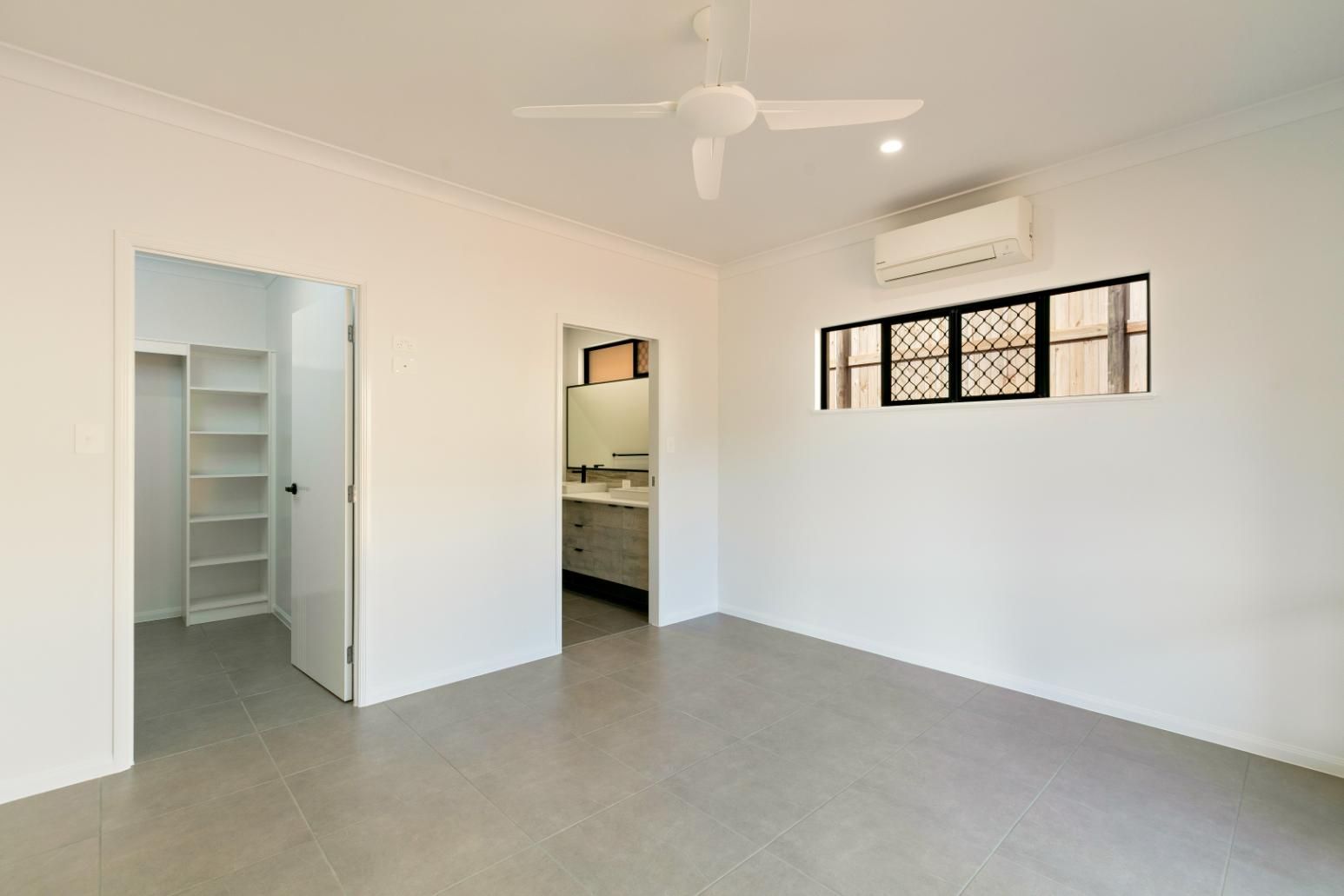An Empty Bedroom With a Ceiling Fan and a Bathroom — Ashlee Jones Homes in Gordonvale, QLD