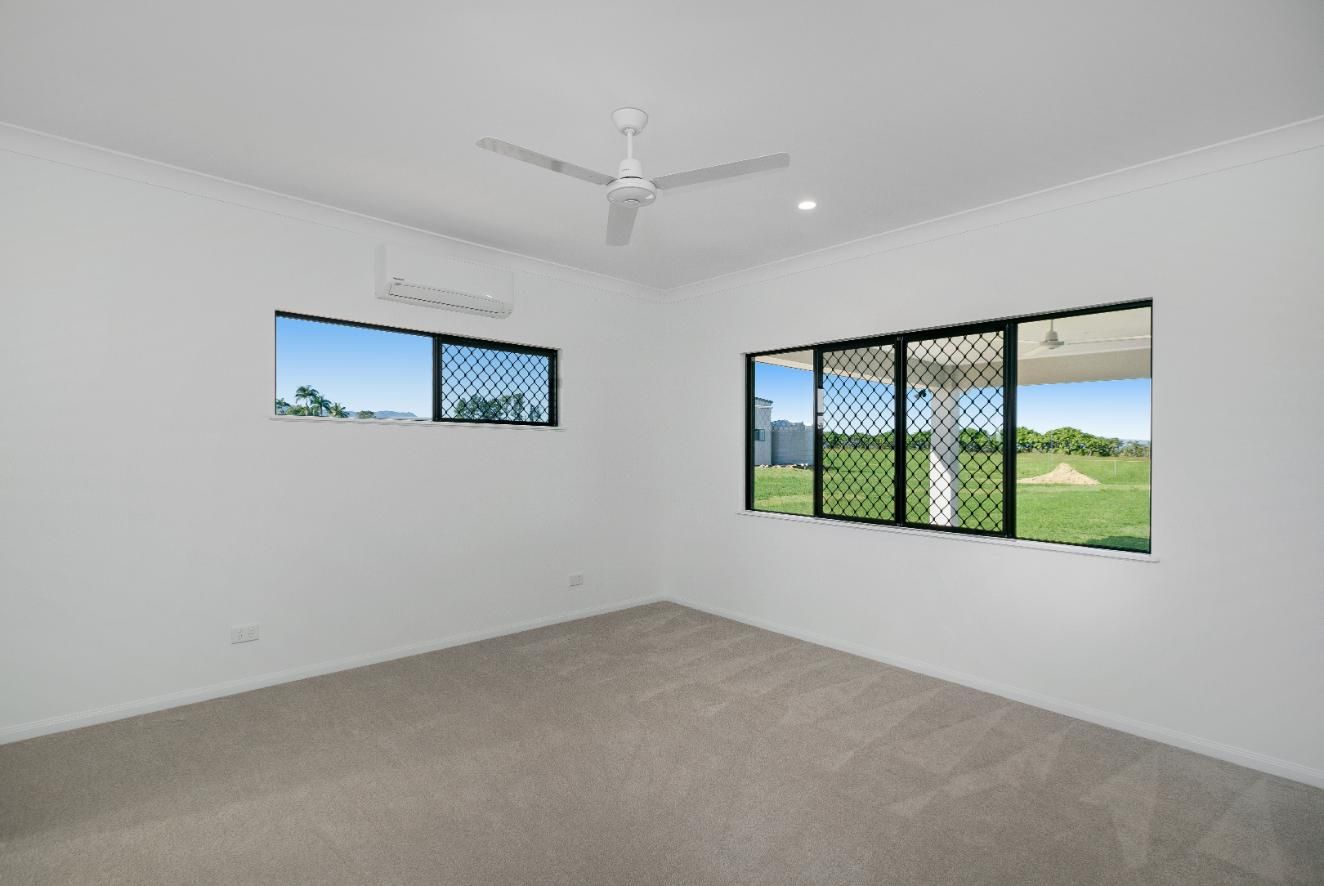 An Empty Bedroom With Two Windows and a Ceiling Fan — Ashlee Jones Homes in Gordonvale, QLD
