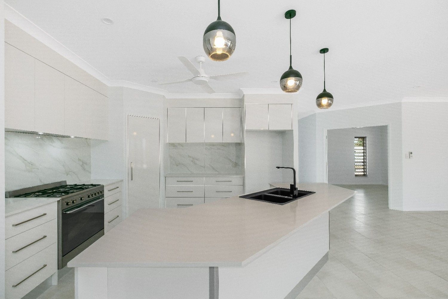 A Kitchen With White Cabinets and a Large Island — Ashlee Jones Homes in Gordonvale, QLD
