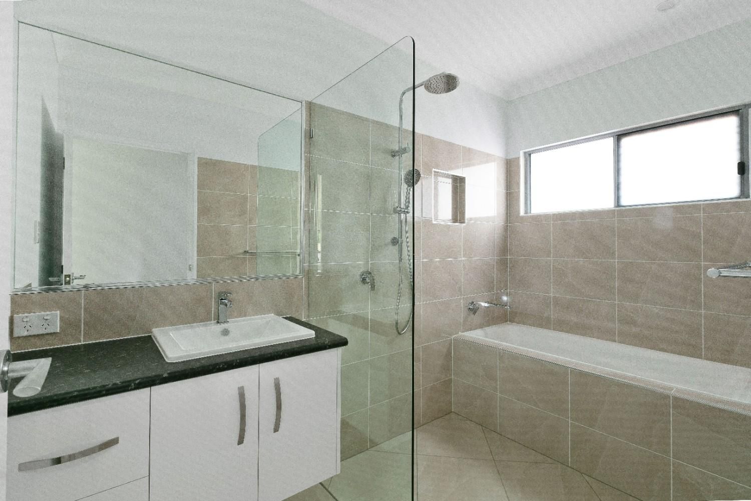 A Bathroom With a Sink, Tub, Shower and Mirror — Ashlee Jones Homes in Gordonvale, QLD
