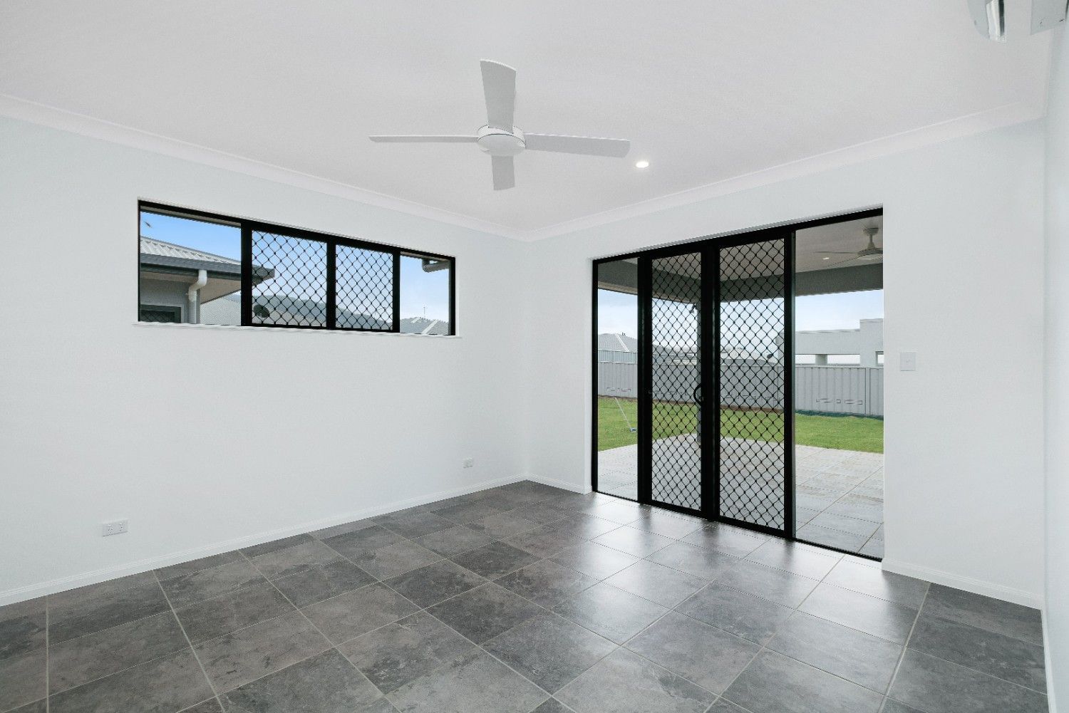 An Empty Room With a Ceiling Fan and Sliding Glass Doors — Ashlee Jones Homes in Gordonvale, QLD