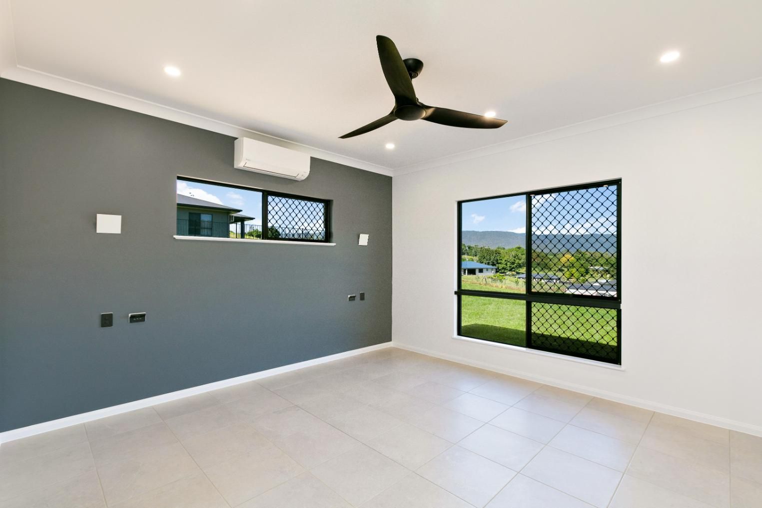 An Empty Room With a Ceiling Fan and Two Windows — Ashlee Jones Homes in Gordonvale, QLD