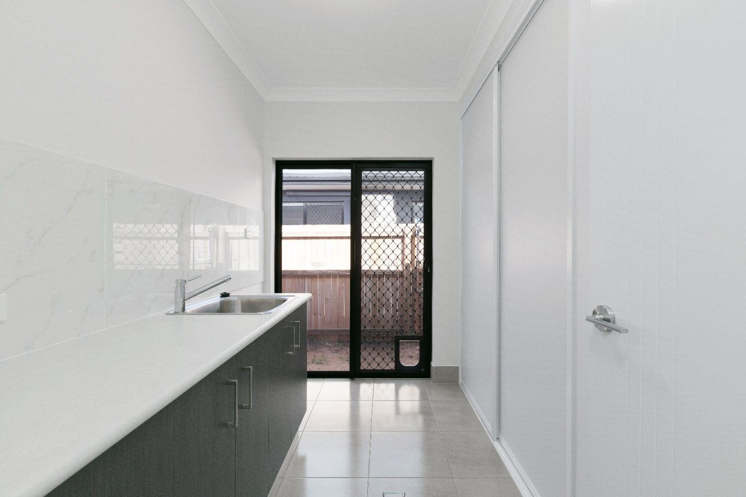 A Kitchen With a Sink, Cabinets and a Sliding Glass Door — Ashlee Jones Homes in Gordonvale, QLD