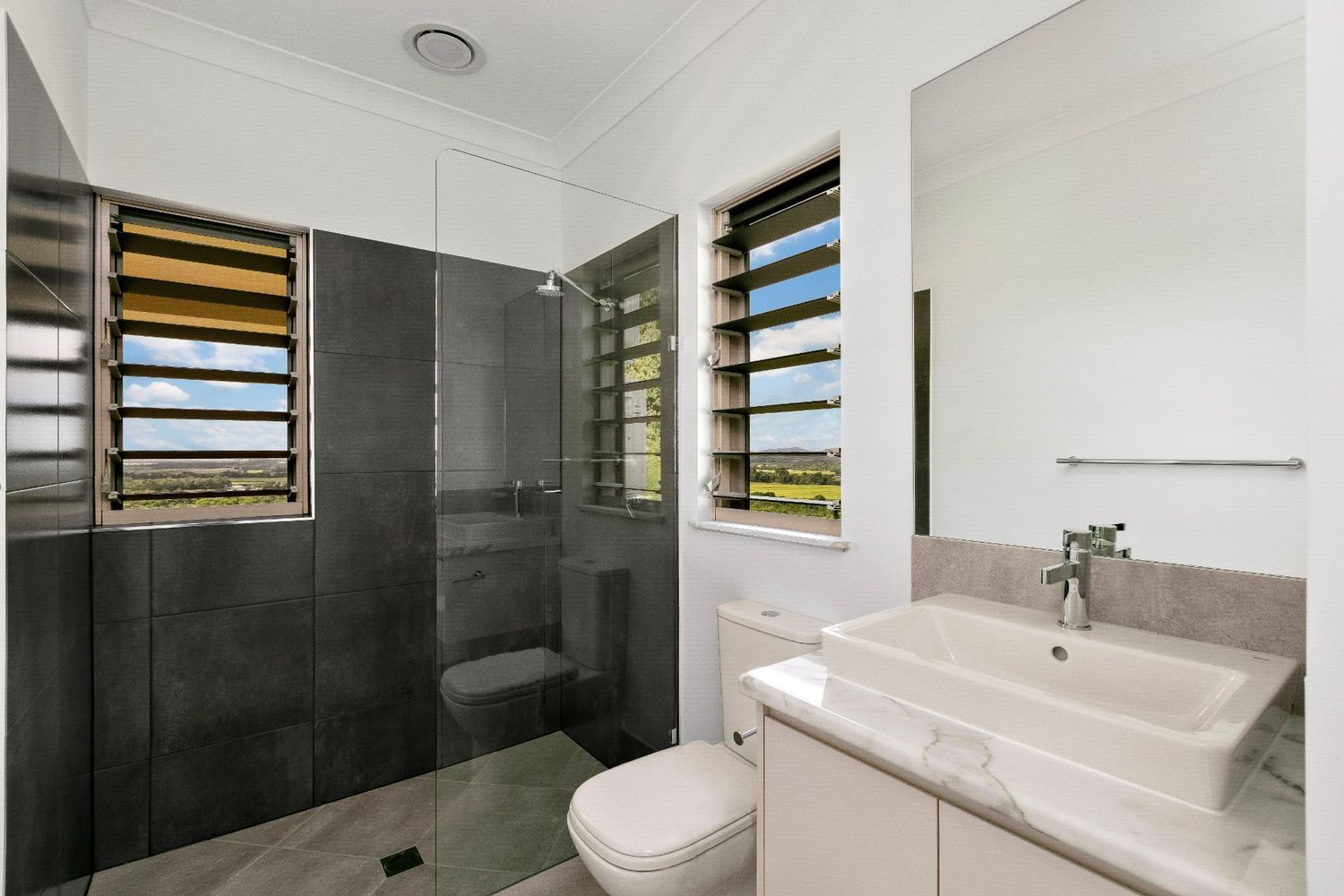 A Bathroom With a Toilet, Sink, and Shower — Ashlee Jones Homes in Gordonvale, QLD