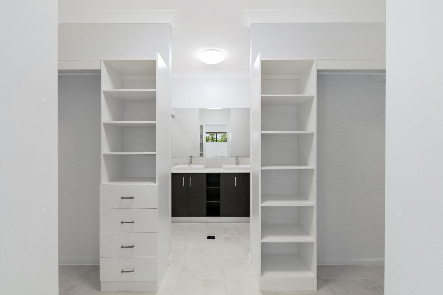 A Walk in Closet With Lots of Shelves and Drawers and a Bathroom in the Background — Ashlee Jones Homes in Gordonvale, QLD